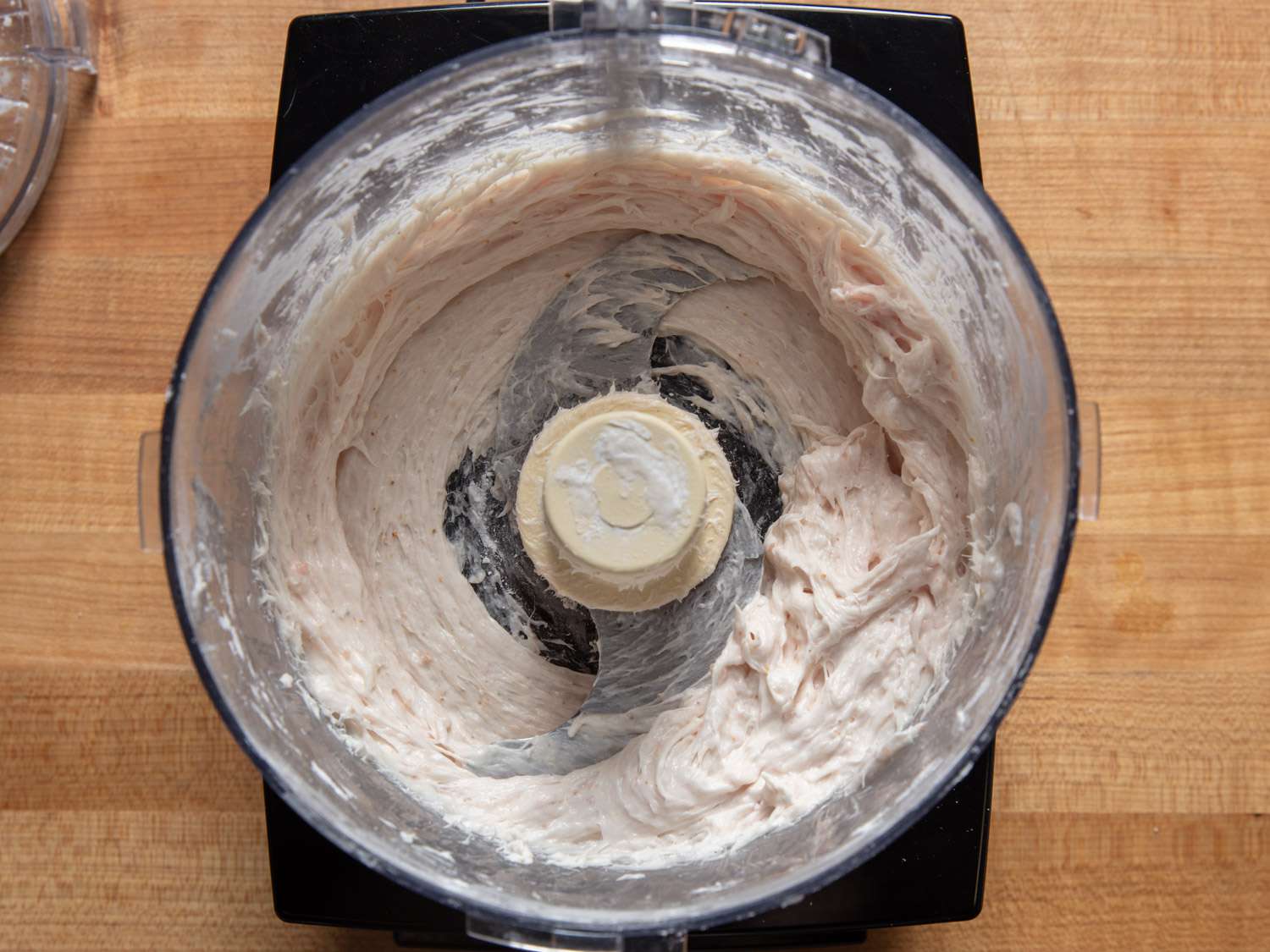 Overhead view into a food processor with squid and pork processed to a very smooth paste.