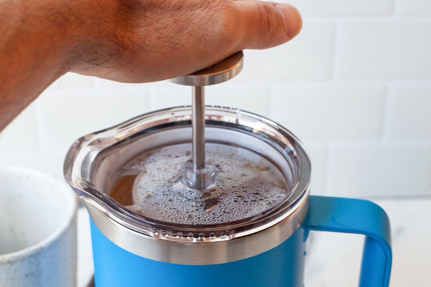 A hand pressing on the top of the Yeti French Press