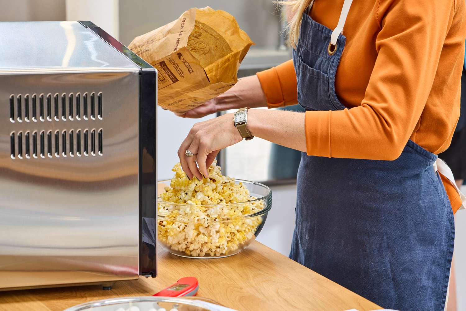 A person emptying a package of popcorn next to the Panasonic - 2.2 Cu. Ft. 1250 Watt SD987SA Full-Size Microwave with Inverter