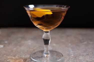 A martinez cocktail in a glass with a lemon twist. 