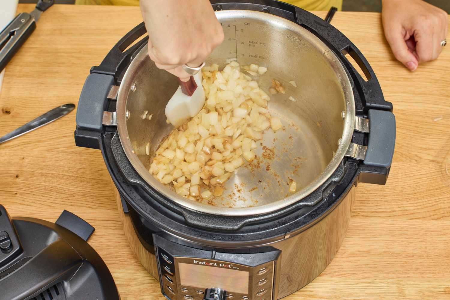 A person cooks onions inside the Instant Pot Pro 10-in-1 6-Quart Pressure Cooker