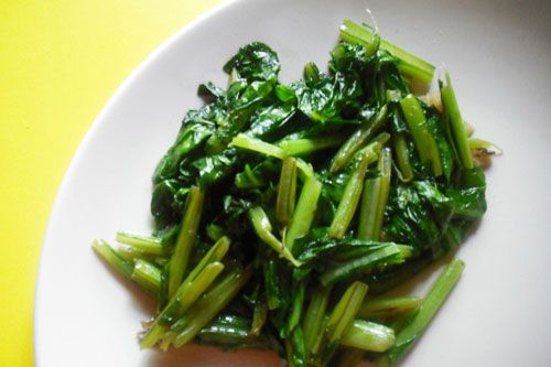Stir-fried Asian leafy greens on a white plate. 
