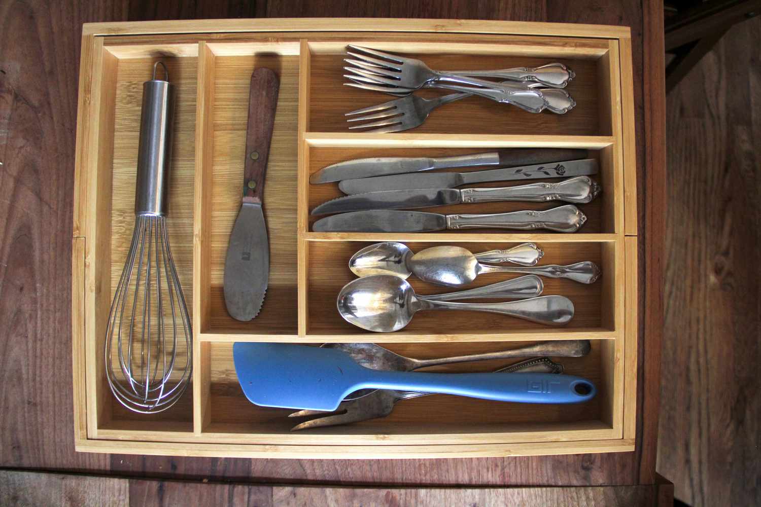A wooden kitchen drawer organizer on a wooden countertop.