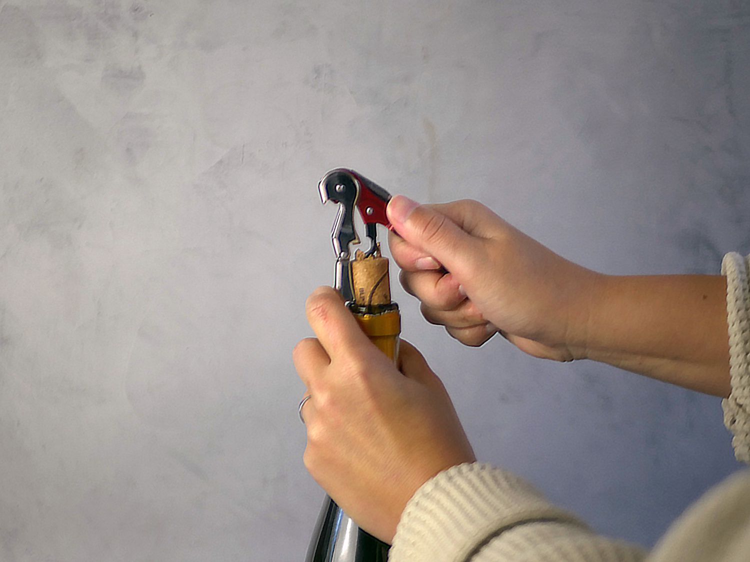 a person opening a bottle of wine using the first fulcrum to begin to lever out the cork.