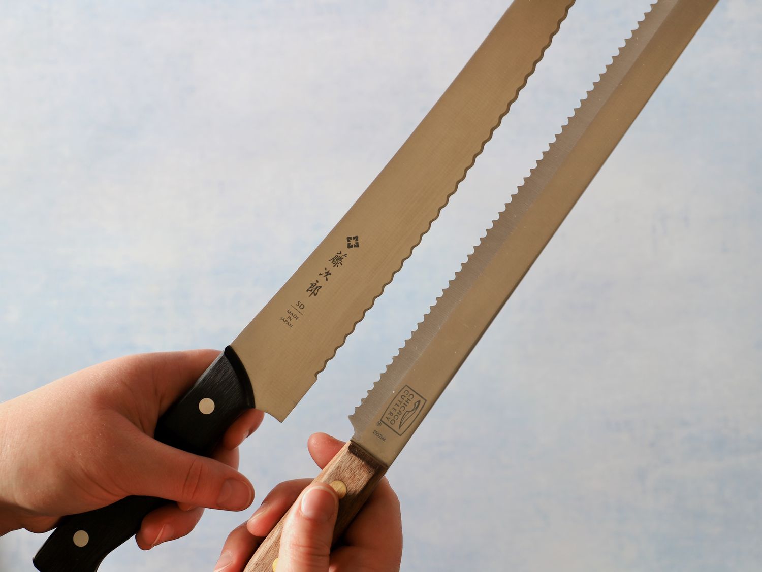 Hands holding two different bread knives side-by-side