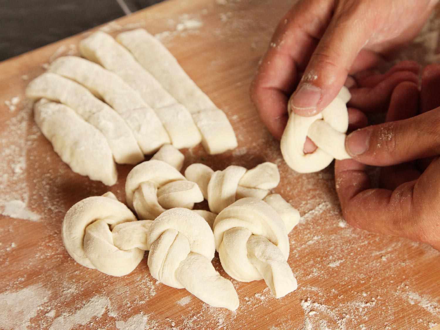 Tying knots of fresh dough for pepperoni garlic knots