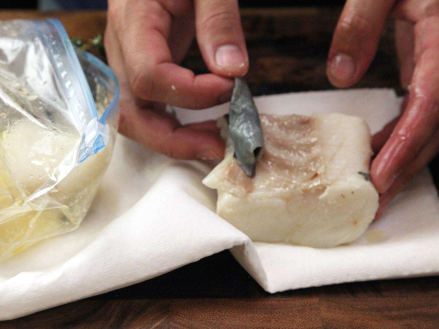Removing a piece of skin from a cut of halibut. 