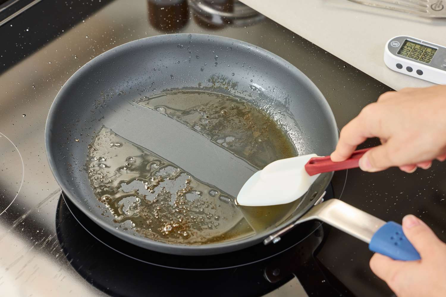 A person scrapes the bottom of the Misen Pre-Seasoned 10 Inch Carbon Steel Pan with a rubber spatula to reveal a clean surface
