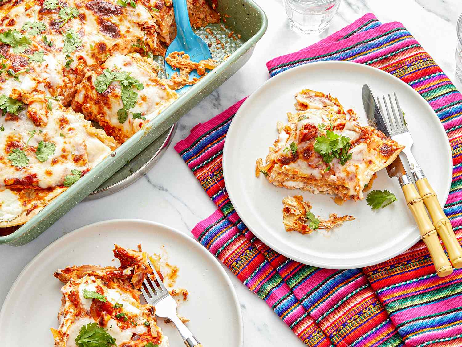 A baked pastel azteca dish with plated servings next to it