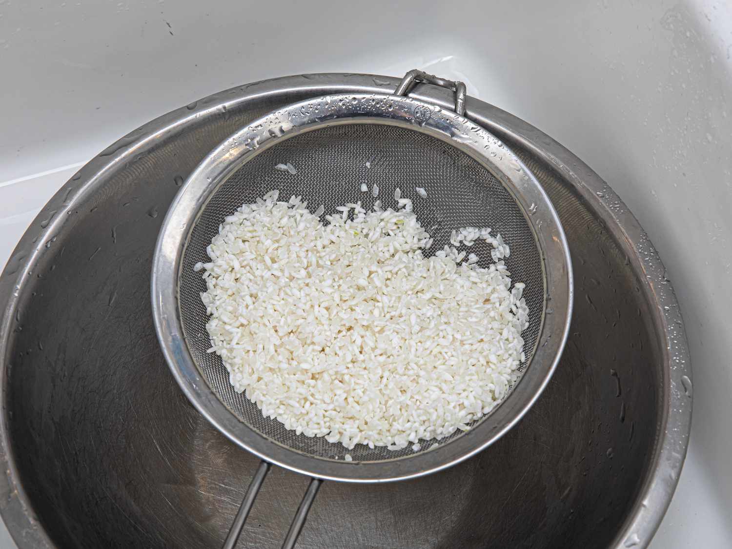 Overhead view of rice draining into a bowl
