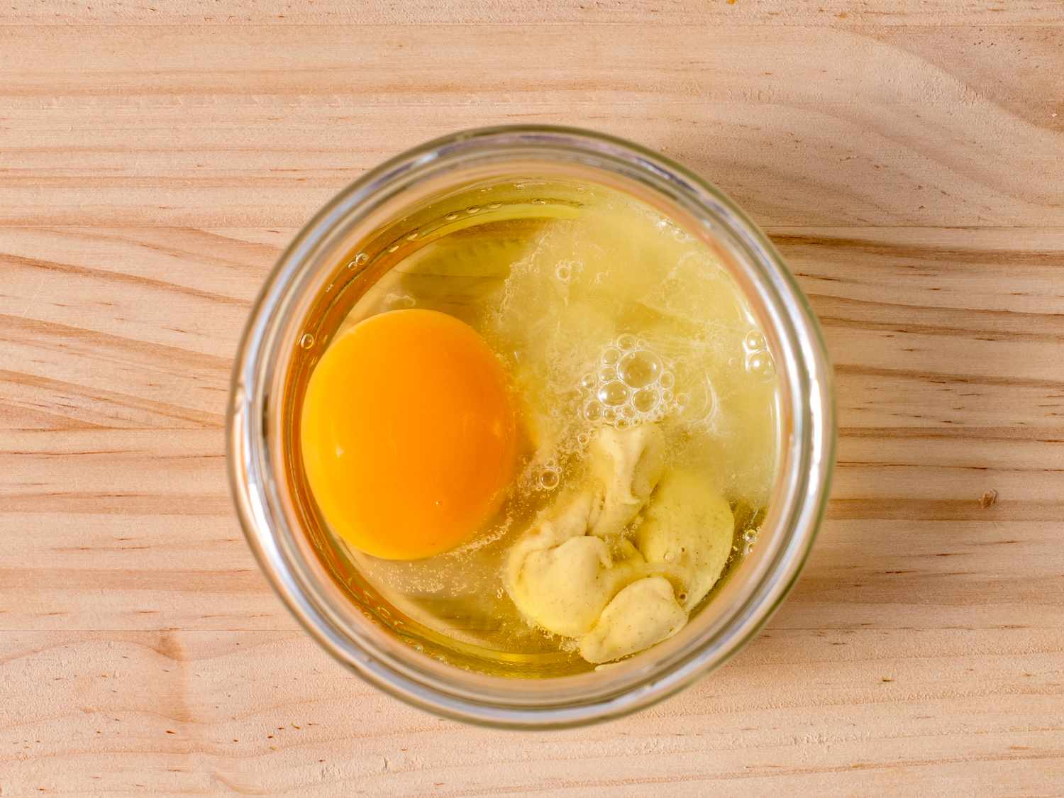 Egg, lemon juice, and mustard in the bottom of a glass jar just large enough to fit the head of an immersion blender.