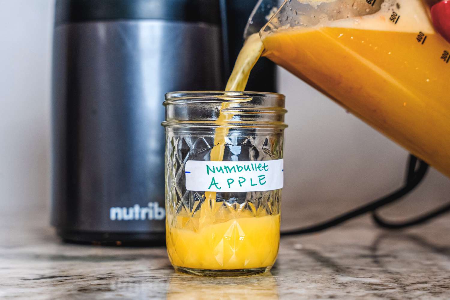 Apple juice being poured into a mason jar after being juiced in a Nutribullet juicer