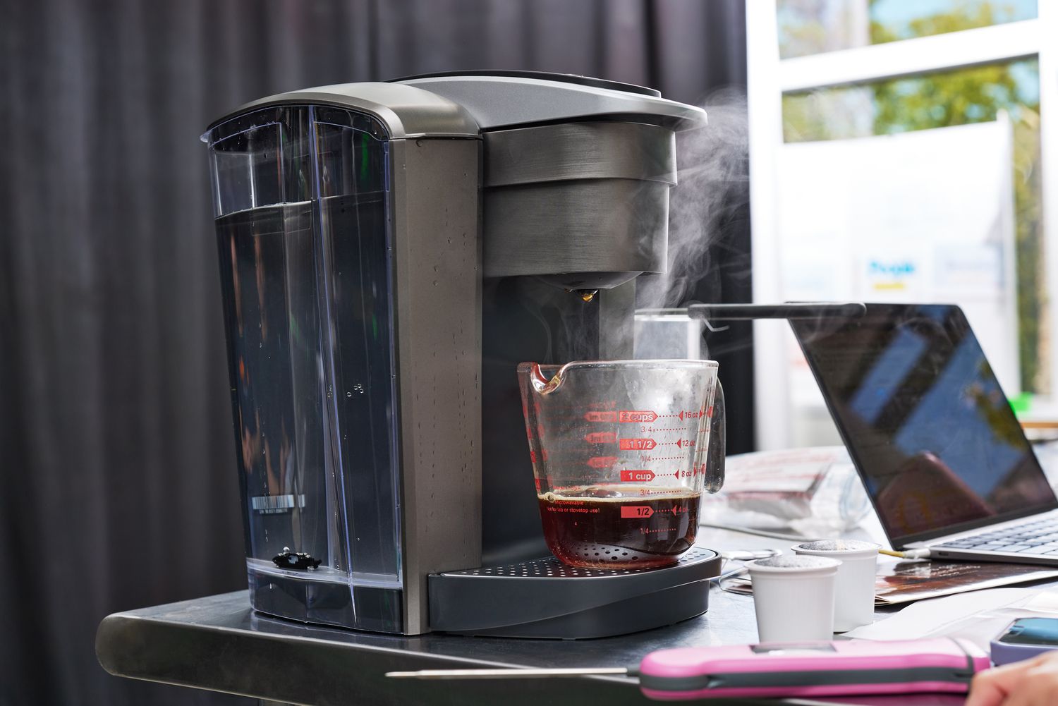 A keurig brewing coffee into a measuring cup