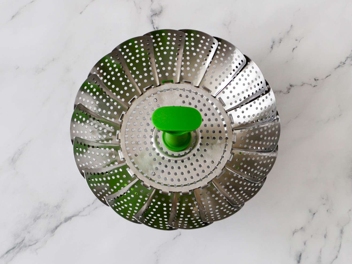 a stainless steel steamer basket on a marble surface