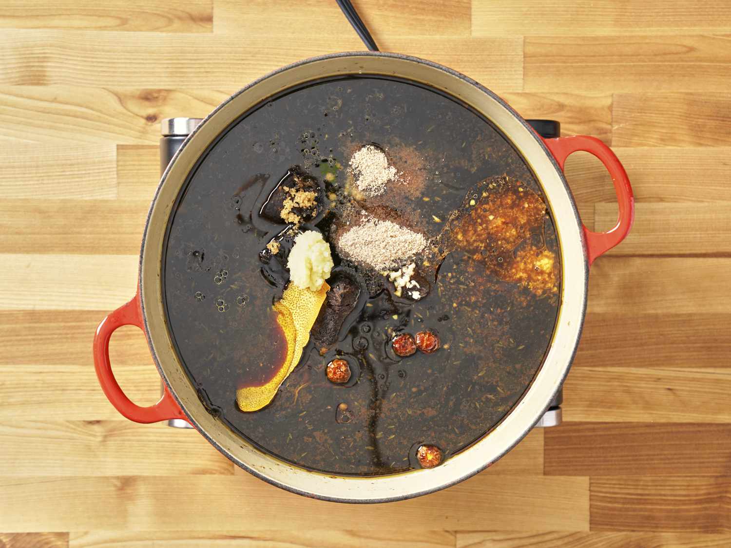 Garlic and orange peel added to Dutch oven.