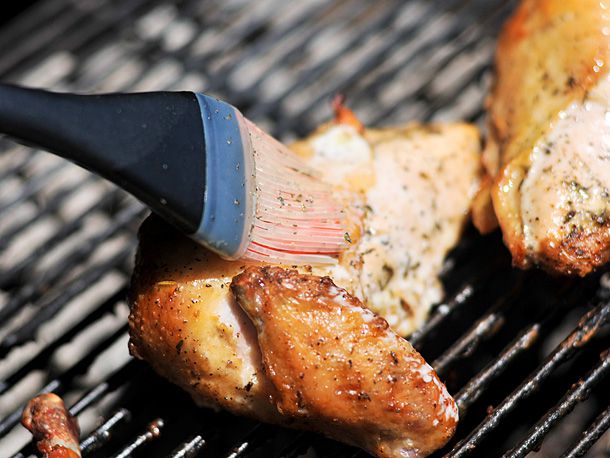 The chicken is basted on the grill.