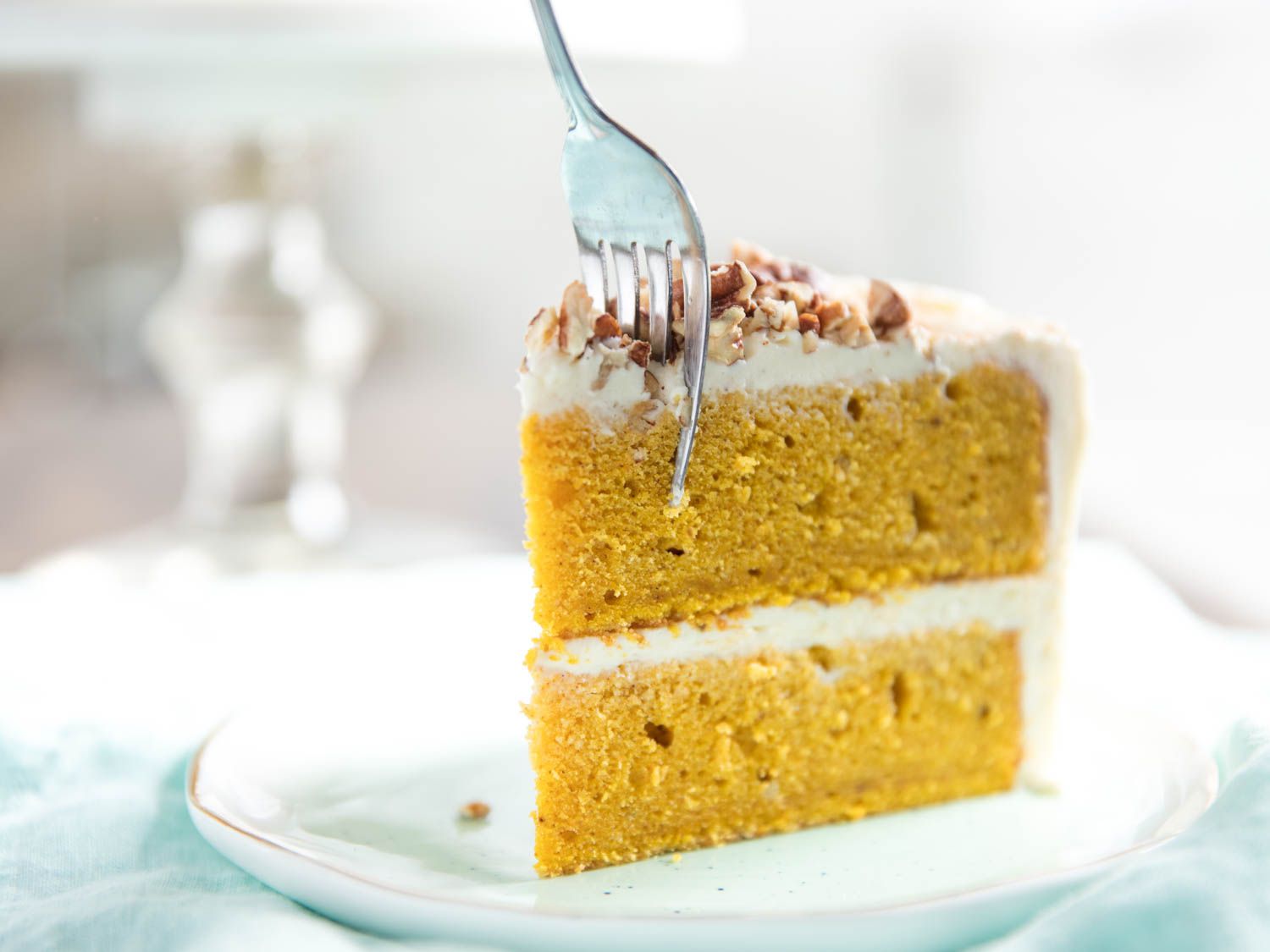 A fork excavates a bite from a slice of pumpkin cake.