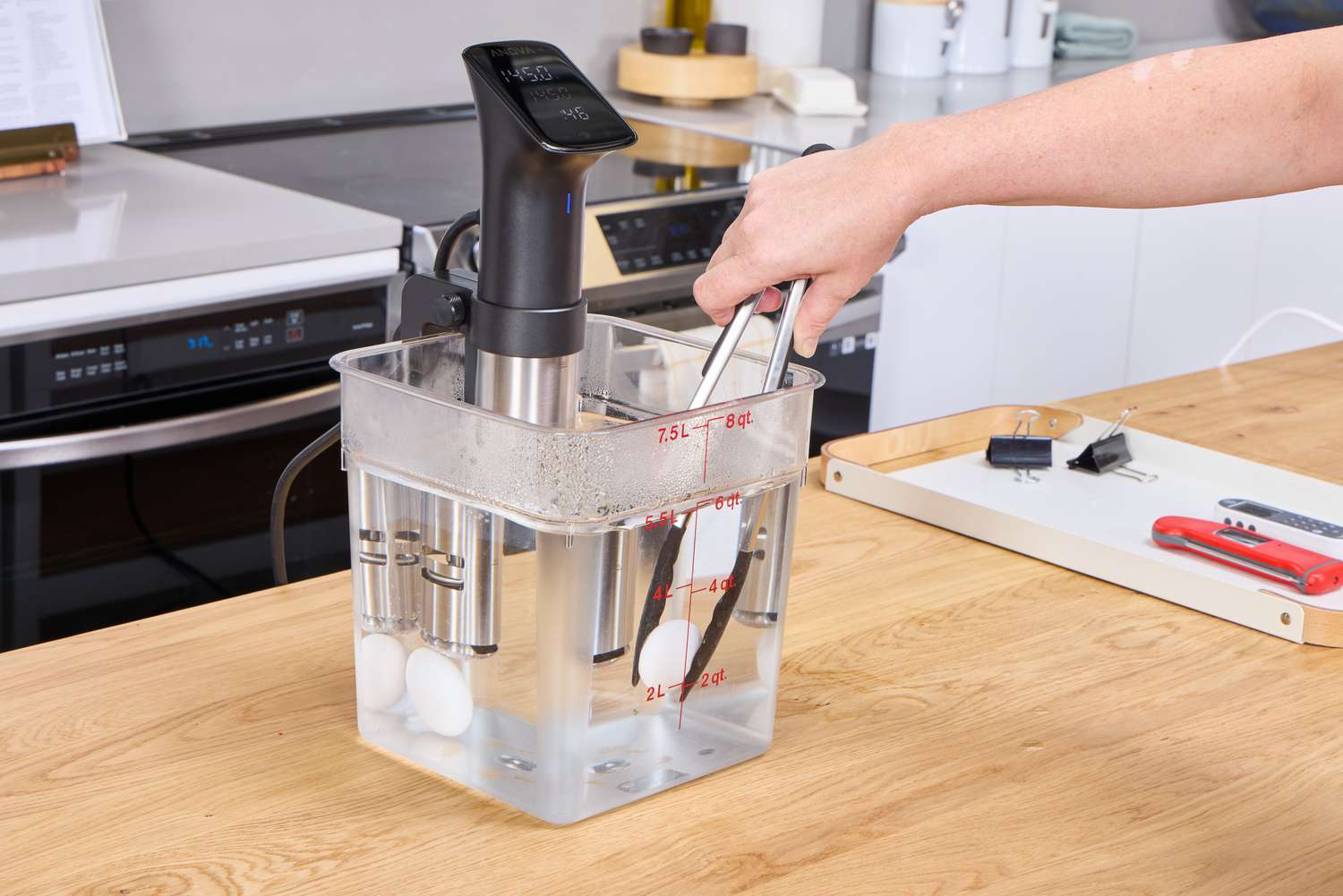 A person removes eggs from water boiled using the Anova Culinary Precision Cooker Pro
