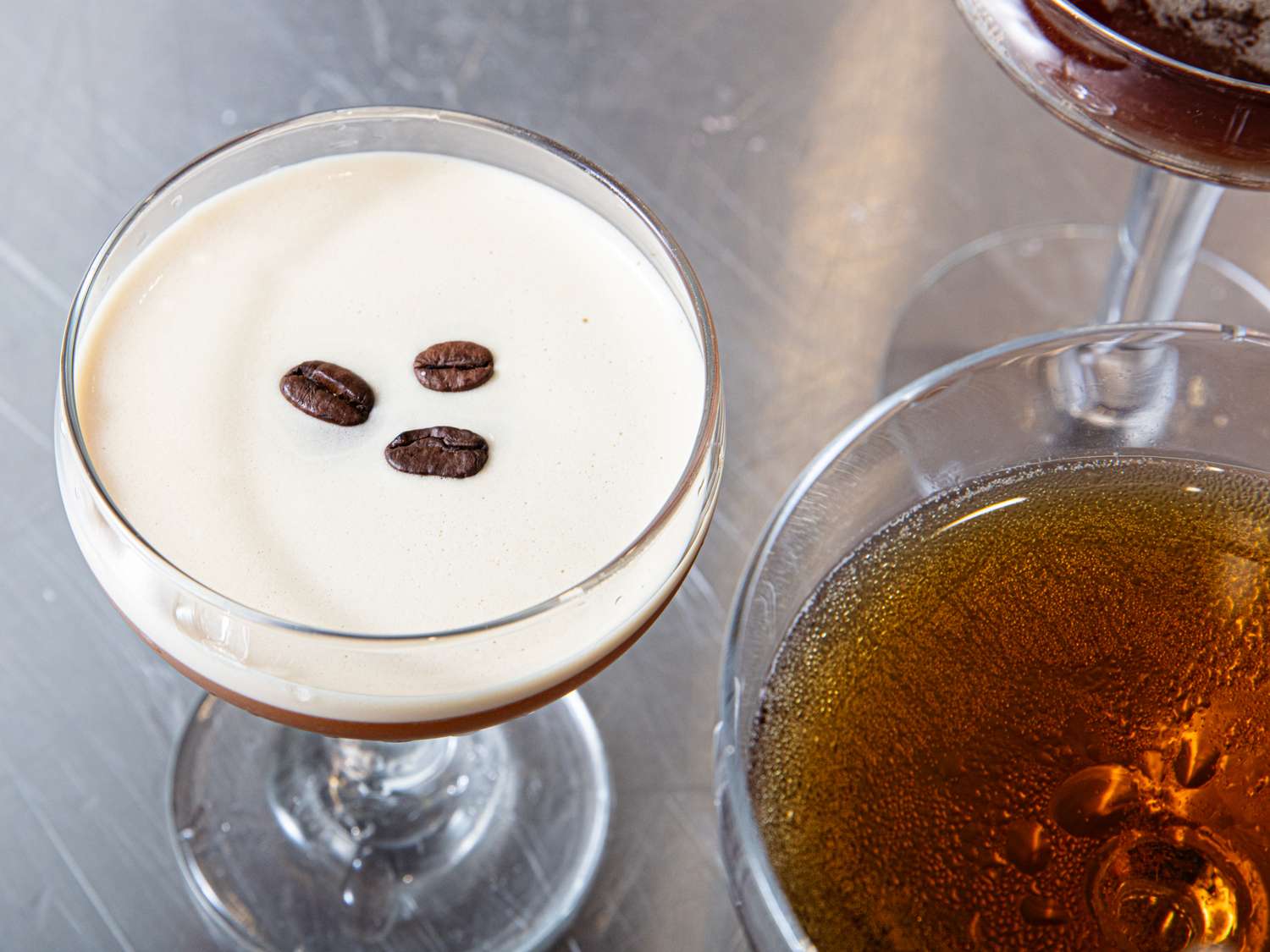 Espresso martinis in cocktail glasses one garnished with coffee beans