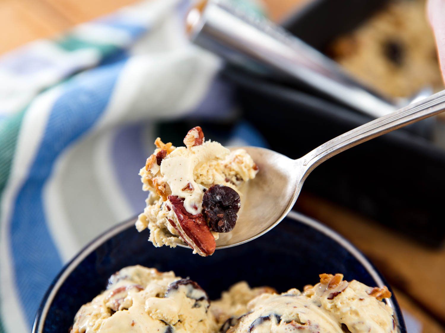 A spoonful of oatmeal cookie ice cream lifted from a black bowl containing some scoops of ice cream.