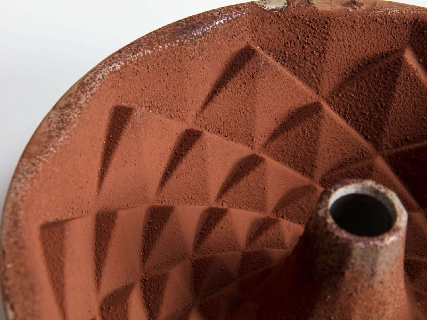 Closeup of a bundt pan with the inside dusted with cocoa powder to prevent sticking.