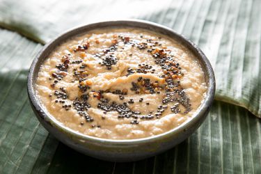 A bowl of coconut chutney served on a surface covered with a banana leaf.