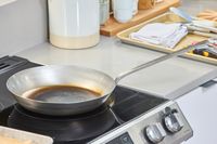 The Vollrath 12.5 Inch French Style Carbon Steel Fry Pan on a stovetop