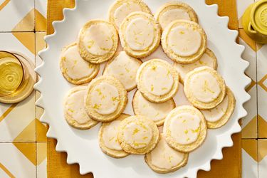 Plate of lemon sugar cookies on a yellow textile on top of yellow and white tiles. 