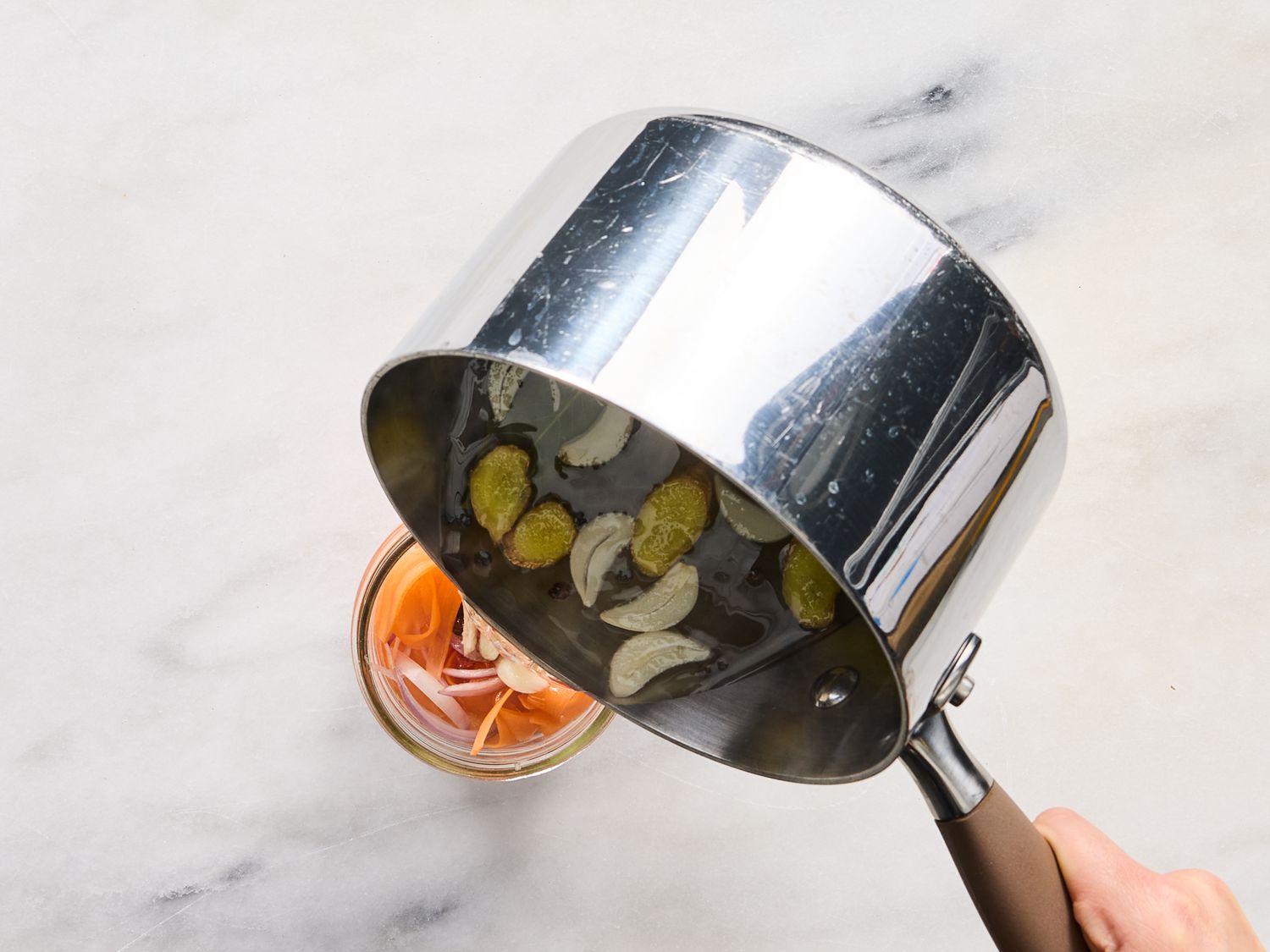 pouring vinegar mixture into jar with carrot ribbons 