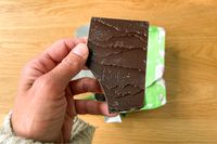 A person holding the The Raaka Pink Sea Salt Dark Chocolate Bar unwrapped