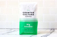 A bag of Counter Culture Coffee, labeled Big Trouble with tasting notes caramel, nutty, and round, on a white tile background
