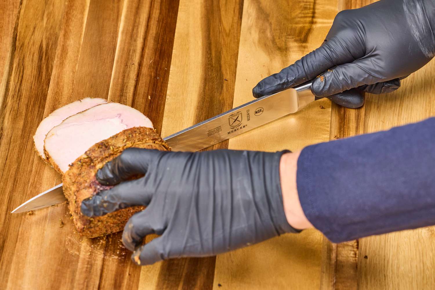 A person slices meat with the Mercer Culinary 10-Inch Carving Knife