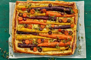 carrot tart on a sheet of parchment paper on a green wooden surface 