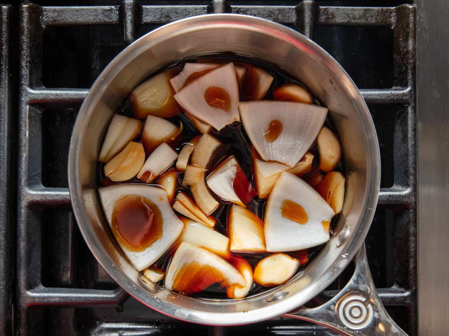 Saucepan of soy sauce pickling liquid with onion and garlic.