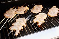 Various types of skewers cooking shrimp on a grill.