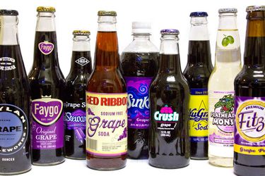 A collection of assorted grape sodas in bottles. 