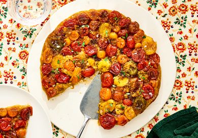 A tomato tart Tatin on a platter garnished with herbs