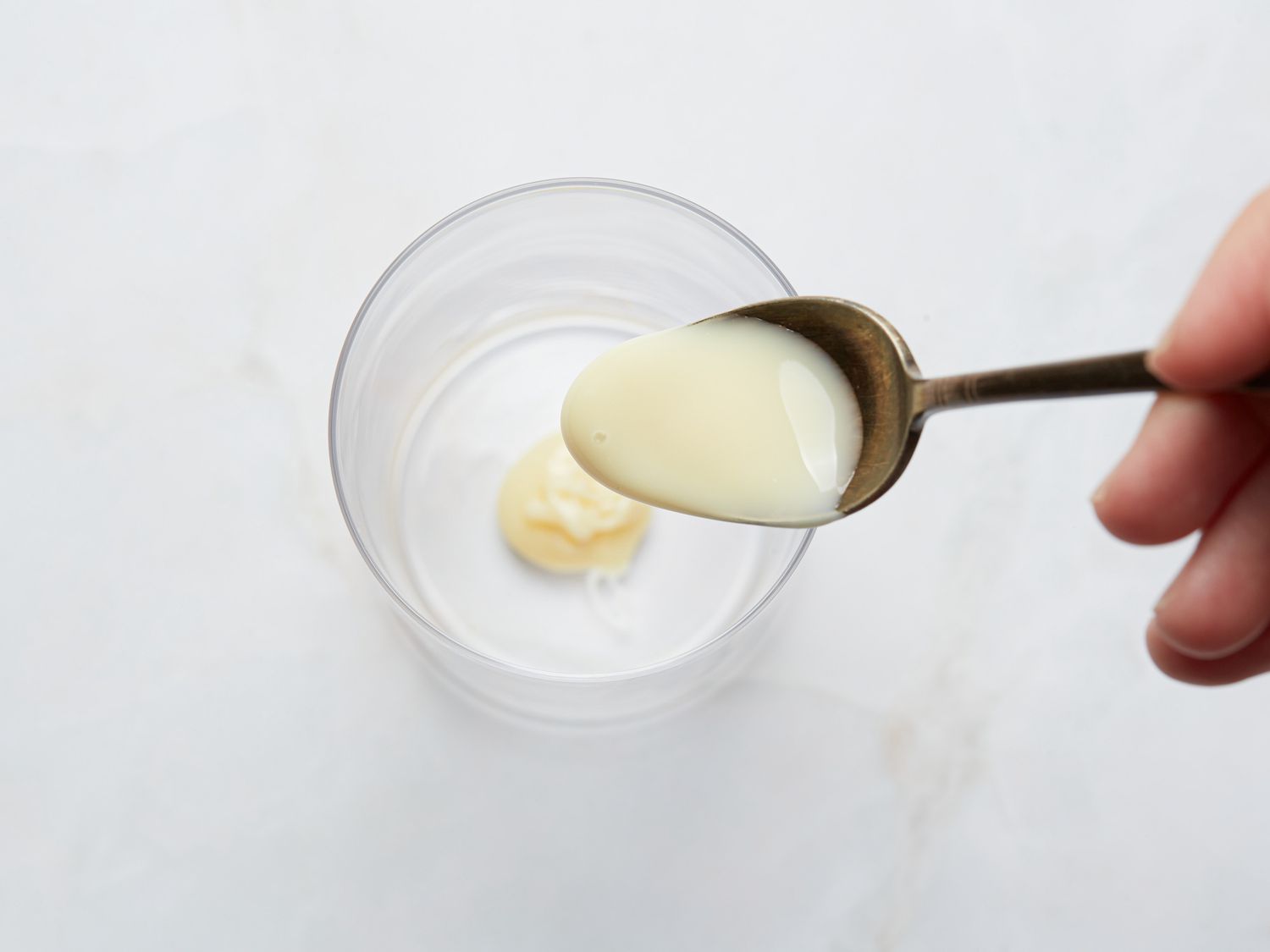 A spoon of condensed milk over a glass.