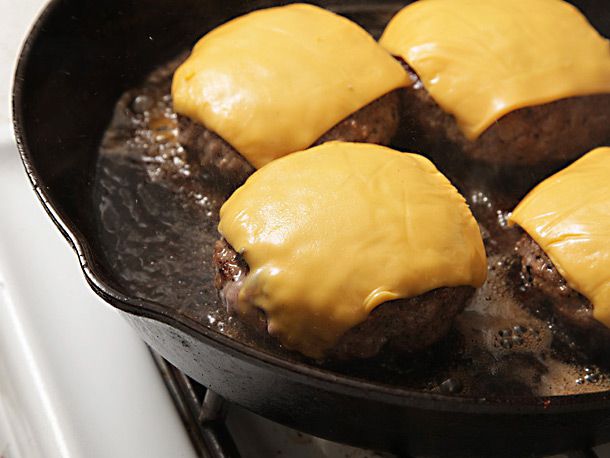The burger patties are topped with melted cheese after the final flip.