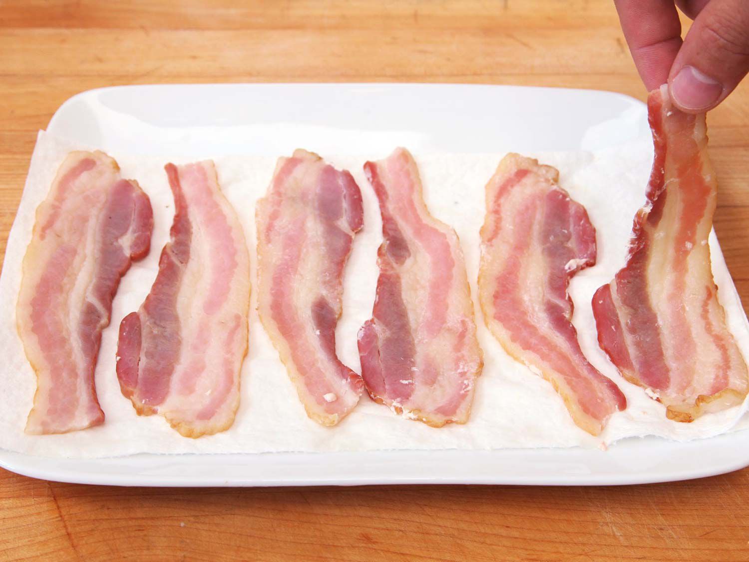 Six slices of cooked (but not browned) bacon on a platter.