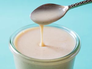 Homemade sweetened condensed milk dripping off a spoon