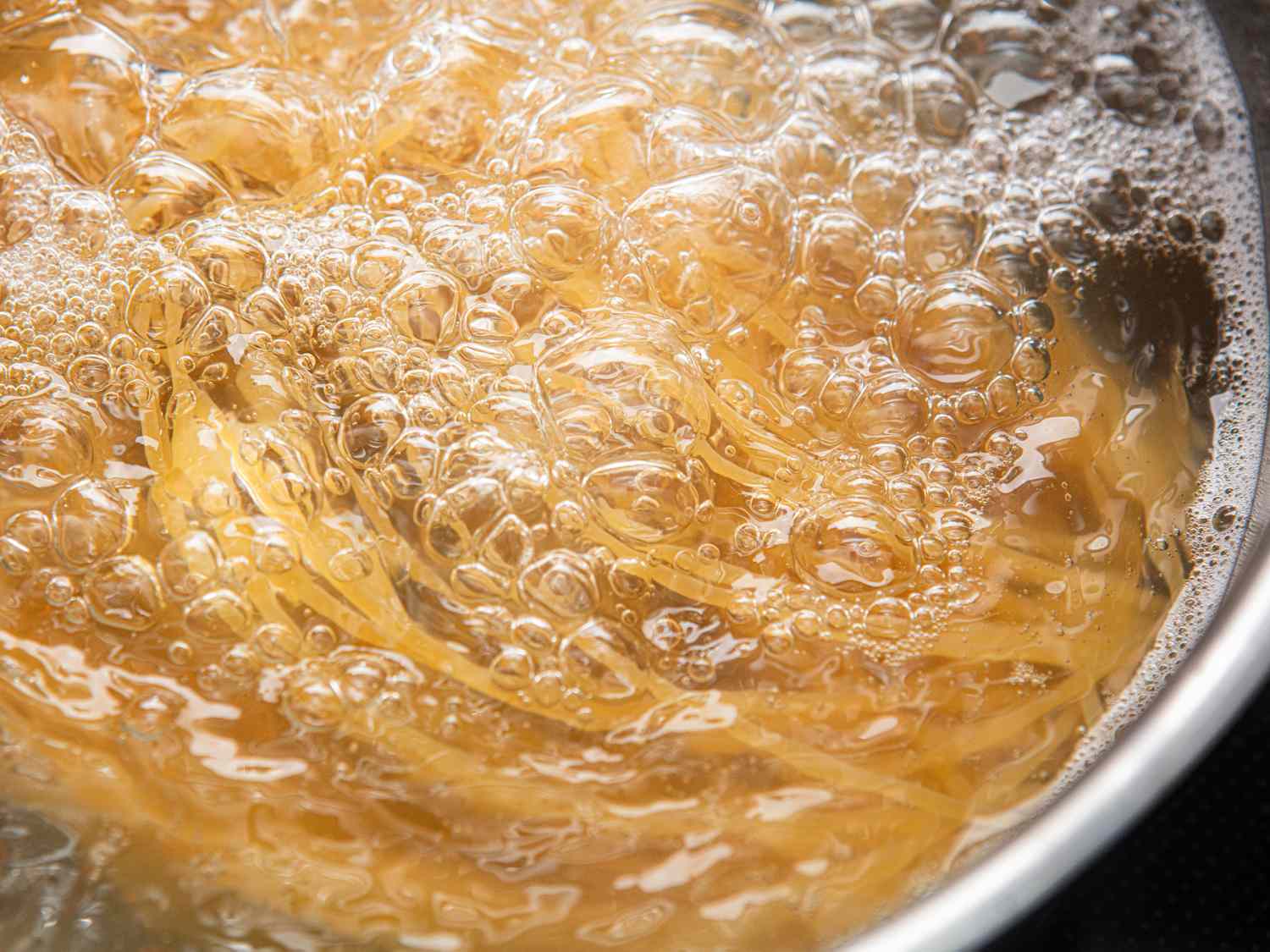 Spaghetti boiling in water creating foam and bubbles