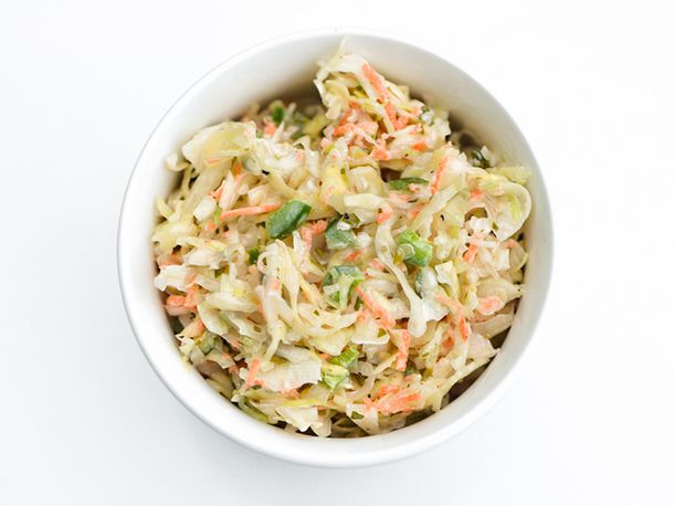 Overhead view of jalapeño coleslaw, served in a white bowl on a white background.