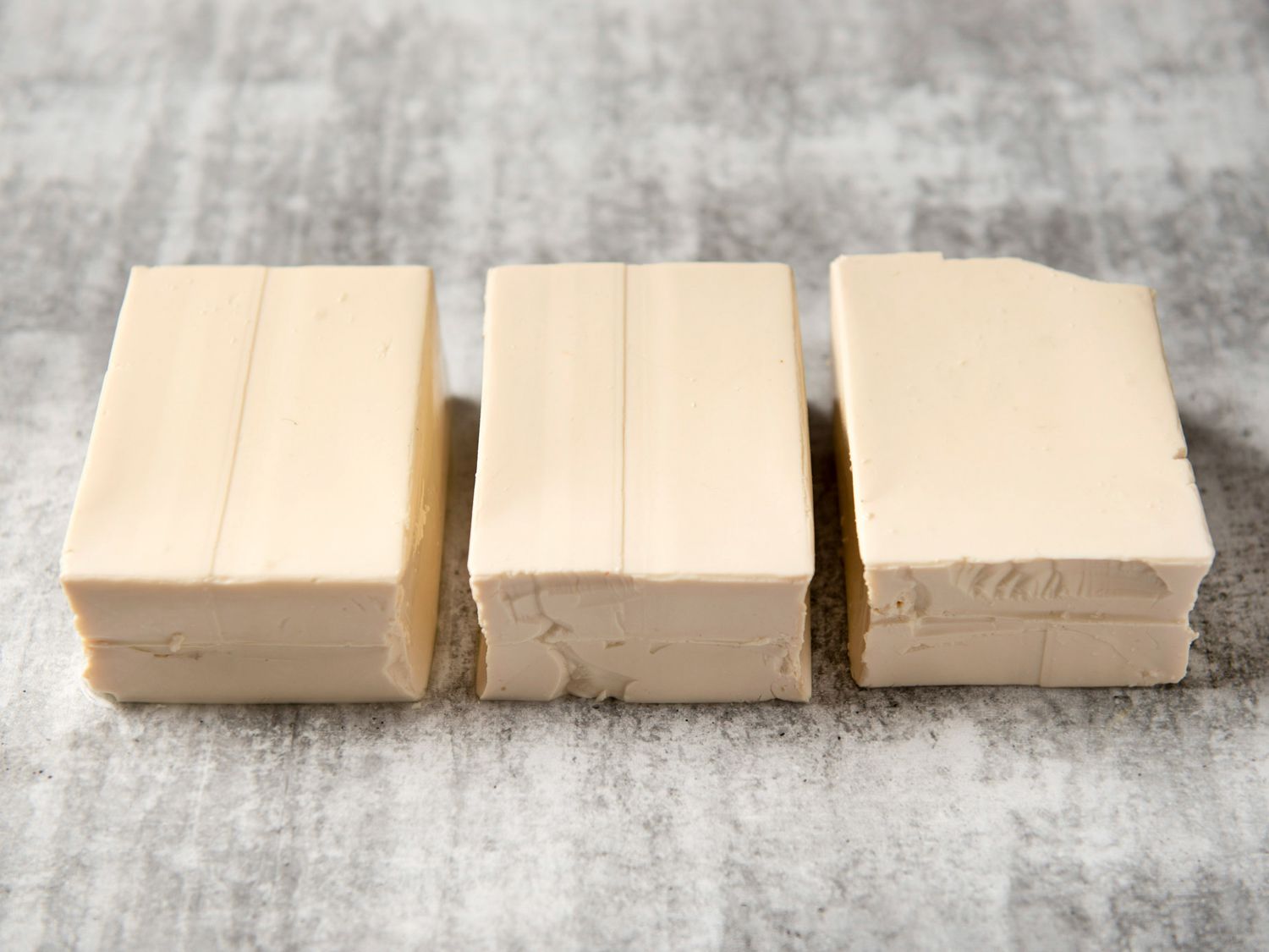 Three blocks of silken tofu side by side on counter