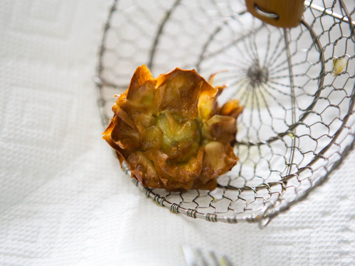 Double-fried "bloomed" artichoke heart in a spider.