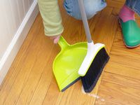 a person sweeping up rice with the casabella dustpan and broom