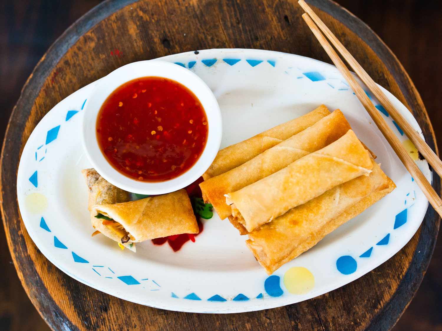 Overhead view of spring rolls served on an an oval plate with a spicy dipping sauce.
