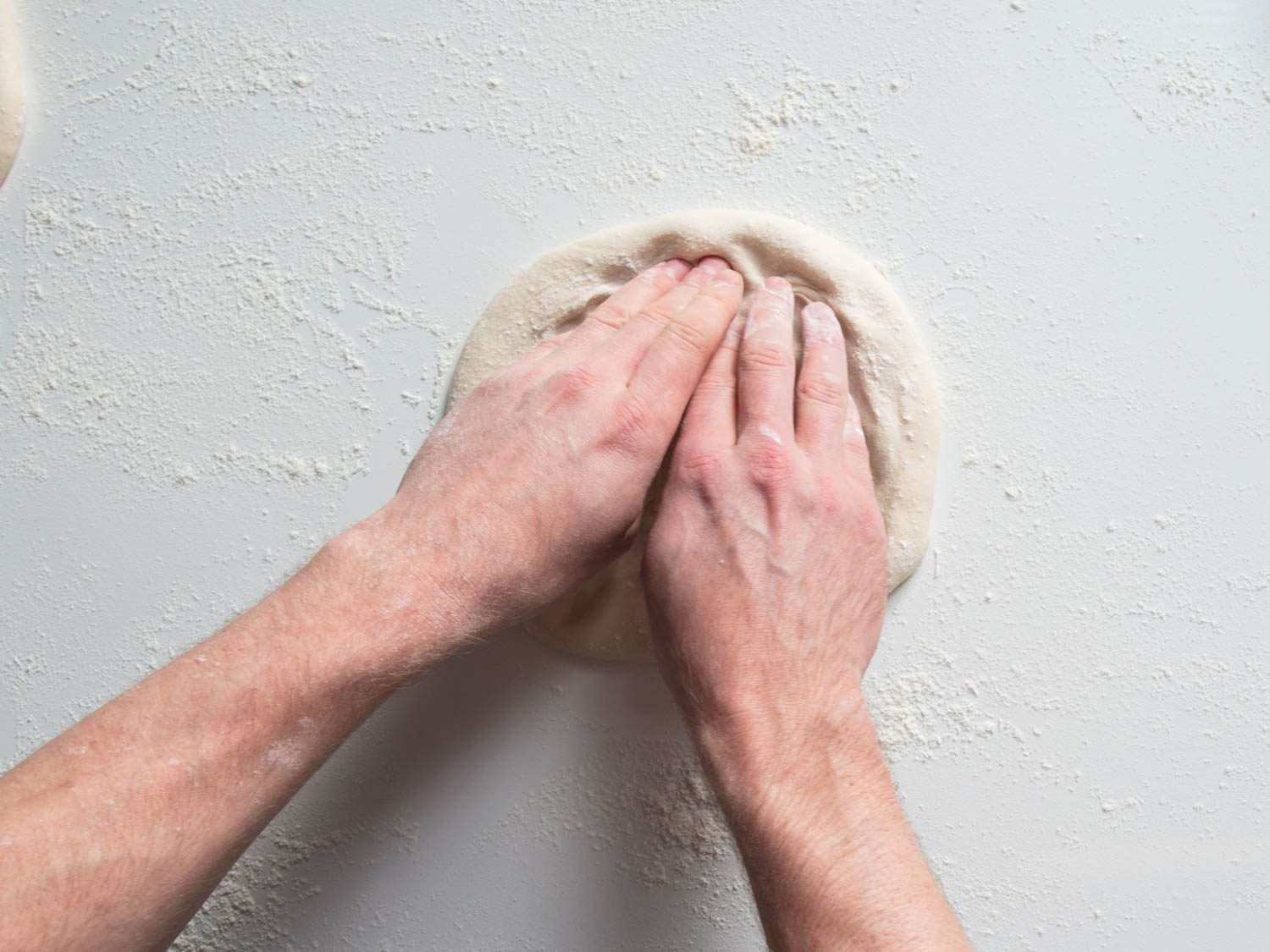 Stretching a ball of pizza dough on a counter.