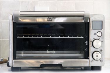 breville compact toaster oven on a white marble counter with white tile backdrop