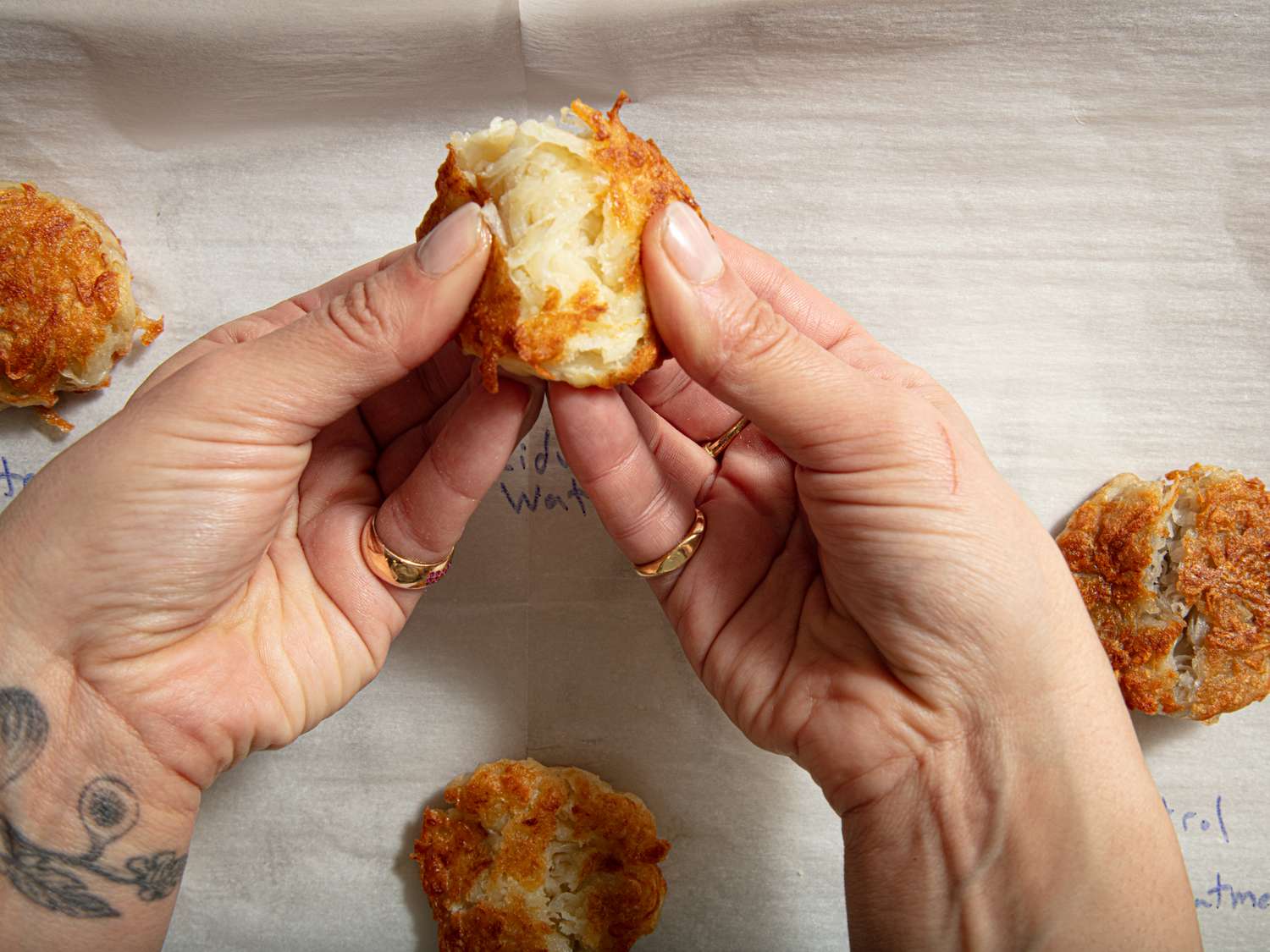 Hands breaking a cooked shredded potato dish on a baking sheet